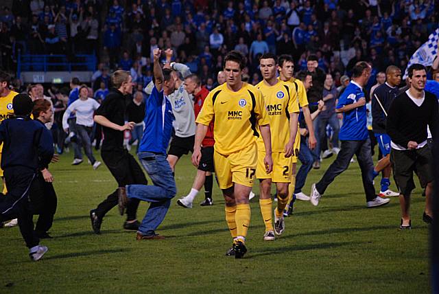Dismayed Dale players leave the pitch as Gillingham fans begin their celebrations.