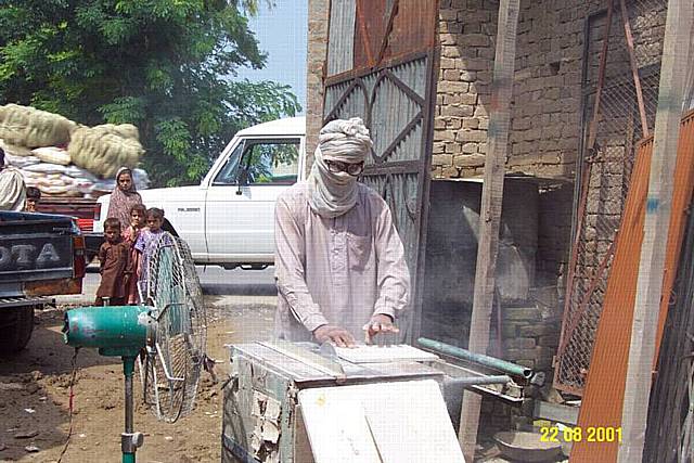 A worker in Pakistan using a power saw to cut asbestos.