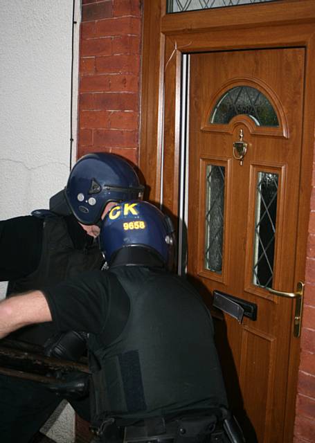 Police use a battering ram to burst through the front door of the Middleton home.