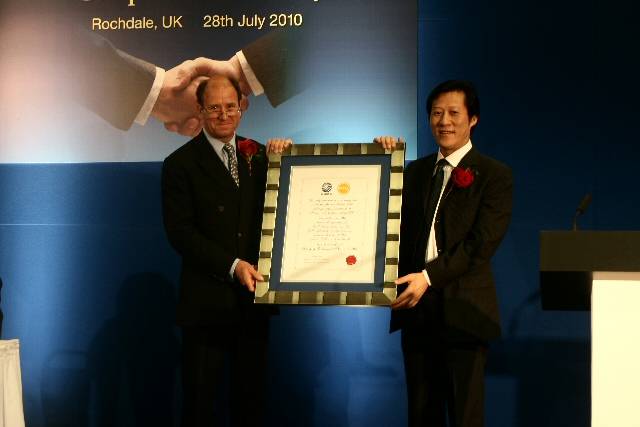 The chairman of PTG, Adrian de Ferranti, presents a certificate in recognition of the transfer to the Chairman of CQME, Mr Xie Huajun
