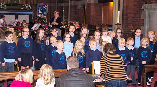 The choir from Holy Trinity, Littleborough with a junior brass band in the background, comprising young musicians from St Andrew's Primary School and from Junior Blast