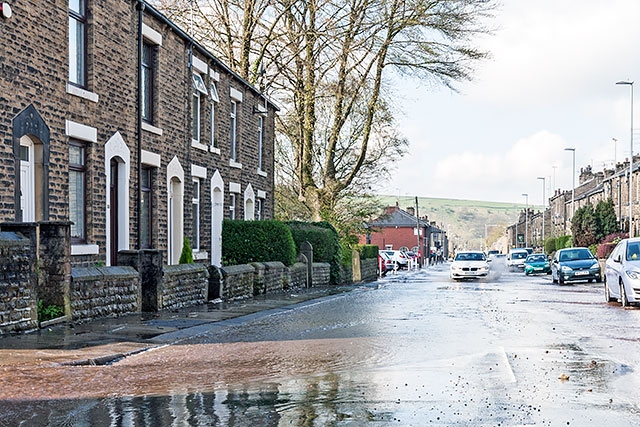 A torrent of water cascading down Huddersfield Road, Newhey