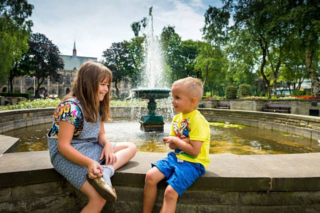 Ella and Louis sit by the fountain at Rochdale Memorial Gardens

