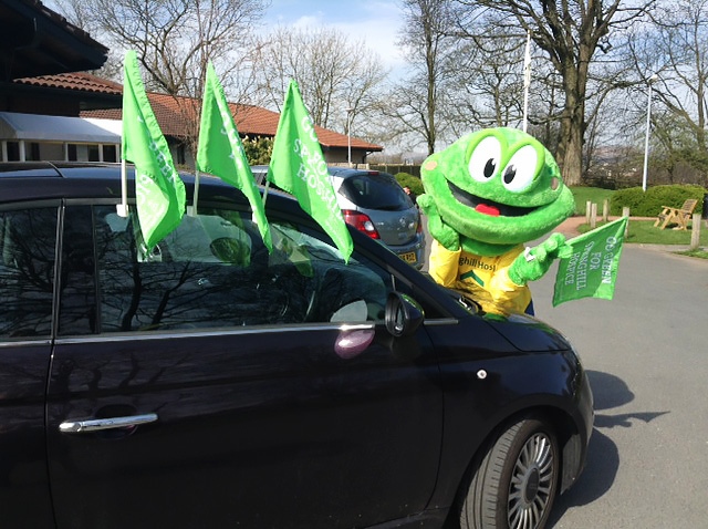 Springy the Hospice Frog decorating cars with Go Green flags