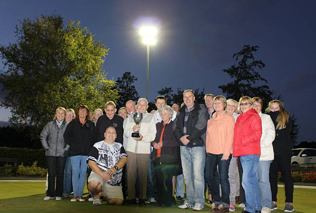 Tommy Whittaker holds the Whittaker Challenge Cup, joined by members of Hare Hill Park Bowls Club underneath the new floodlights 