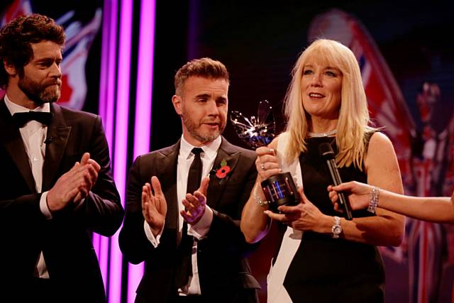 Karen Johnson accepts a Special Recognition Pride of Britain Award from Gary Barlow and Howard Donald of Take That