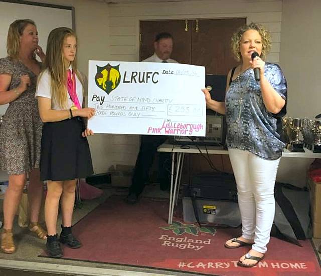 U13s Pink Warriors present a cheque to State of Mind trustee Clair Carson