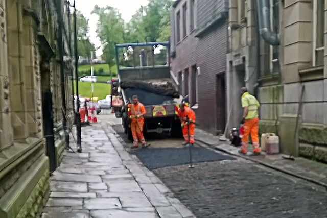 Workmen put temporary tarmac where the setts have been removed on King Street
