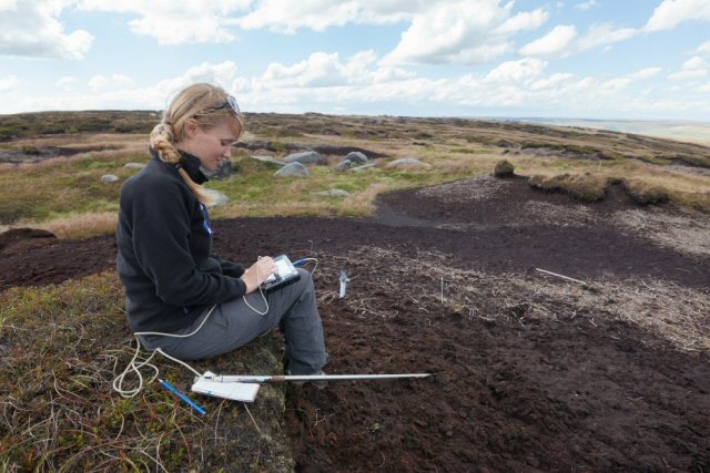 A scientist from Moors for the Future Partnership records the height of the water table on an area of bare peat moorland