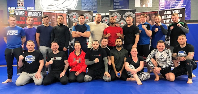 John Kavangh (second from left bottom row) with the Wimp-2-Warrior Manchester Contestants, Coach David Hodkinson left on top row, Coach Derrick Cullen left on bottom row, Head Coach Martin Stapleton right on bottom row
