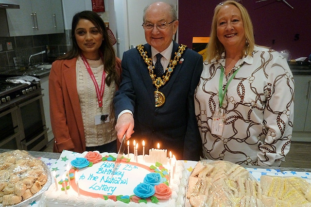 Mayor Billy Sheerin cuts the National Lottery's birthday cake, with Bev Place, business development manager at RCT (right), and a representative from the National Lottery (left)