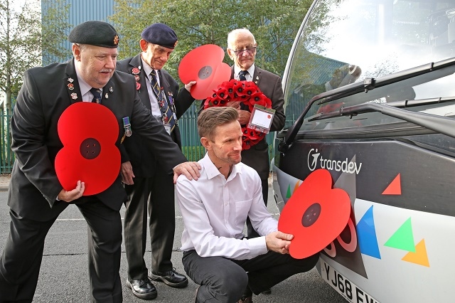 Buses are being adorned with poppies to support the annual Poppy Appeal, as the nation prepares to remember the fallen. From left, veterans Geoff Lister, Michael Scott and Keith Webster watch as engineer Jonathan Ruston fits a poppy to a Transdev bus