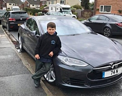 Nathaniel, with his favourite car: a Tesla