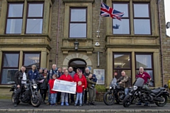 Front centre organisers of the Ring of Red M60 present members of Veterans In Communities with £5,000 from the 2023 Remembrance ride