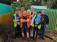 A group of Petrus volunteers and service users, halfway through the build