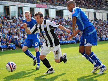 Adam Le Fondre chases the ball down with two Posh defenders for company