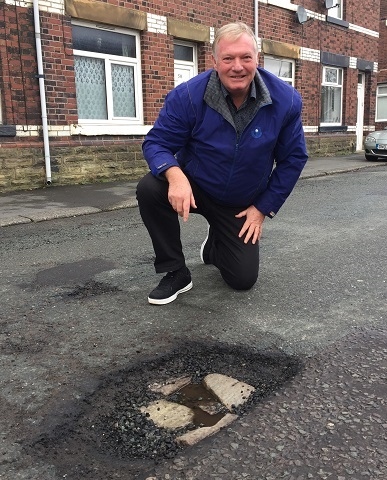 Councillor Neil Butterworth seen here with one of several potholes on Bentgate Street, Newhey