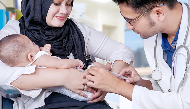 A child being held by his mother whilst being vaccinated by a doctor