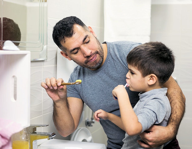 A father and son brushing their teeth at home