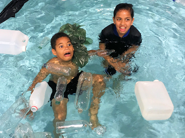 Two children in the pool, surrounded by plastic bottles