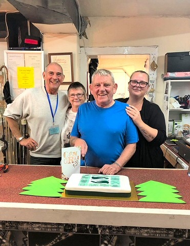 Michael Bamford (centre), who runs Re-Use Littleborough, cut the 1st birthday cake with volunteers