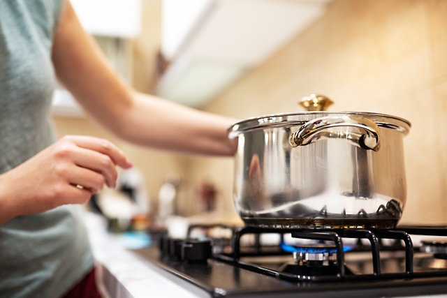 Young woman housewife preparing dinner, hold in hands big steel saucepan, 