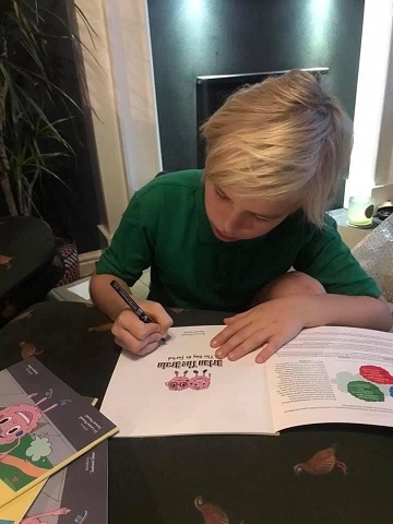 Samuel Mansell signs his book, Brian the Brain, which he co-wrote with his mum
