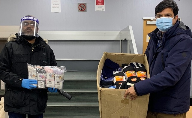 Councillor Faisal Rana (right) handing over lots of socks to Mohammed Sheraz (left) of the Army of Kindness