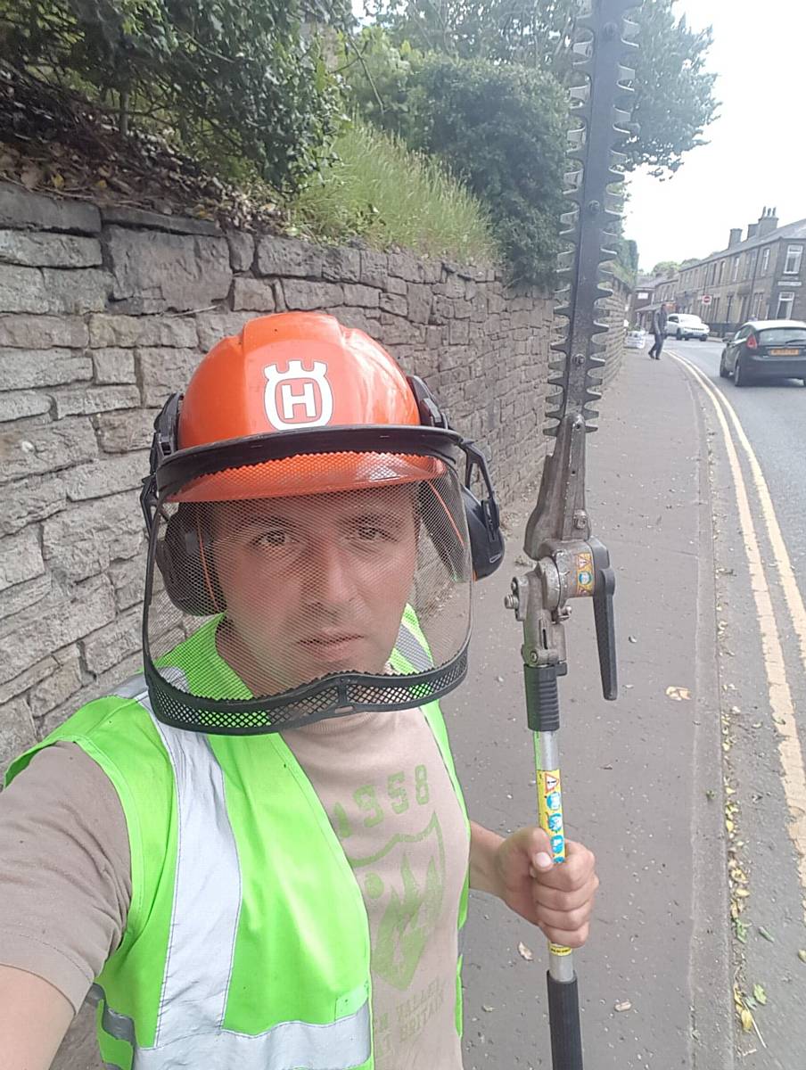 Paul Ellison, dressed in safety gear and armed with a hedgecutter
