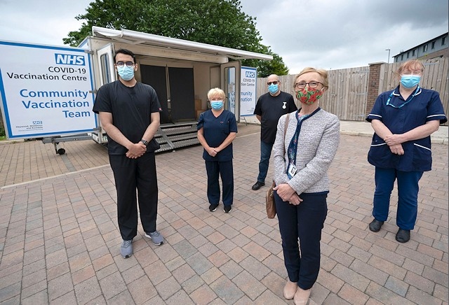 Councillor Patricia Dale, deputy cabinet member for health Rochdale Borough Council (front) with NHS medical staff and the new mobile vaccine unit