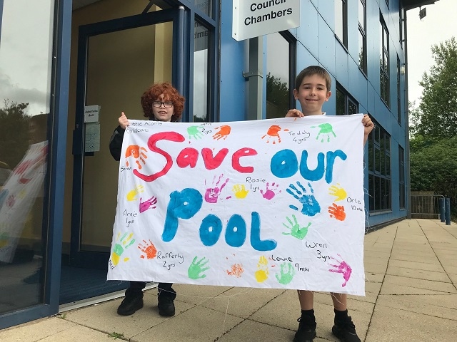 Schoolboys Daley Chianca, left, and William Cromer with a banner about Whitworth Leisure Centre at Rossendale Council. They attend St Bartholomew's School in Whitworth