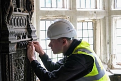 Heritage Building Skills Programme apprentice inspects detailed 18th century wood panels inside Hopwood Hall 